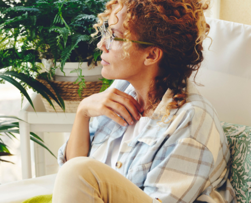 Thoughtful woman witting outdoor home in the terrace looking on her side. Portrait of young adult middle age single lady pensitive. Lady thinking and enjoying relax leisure activity alone